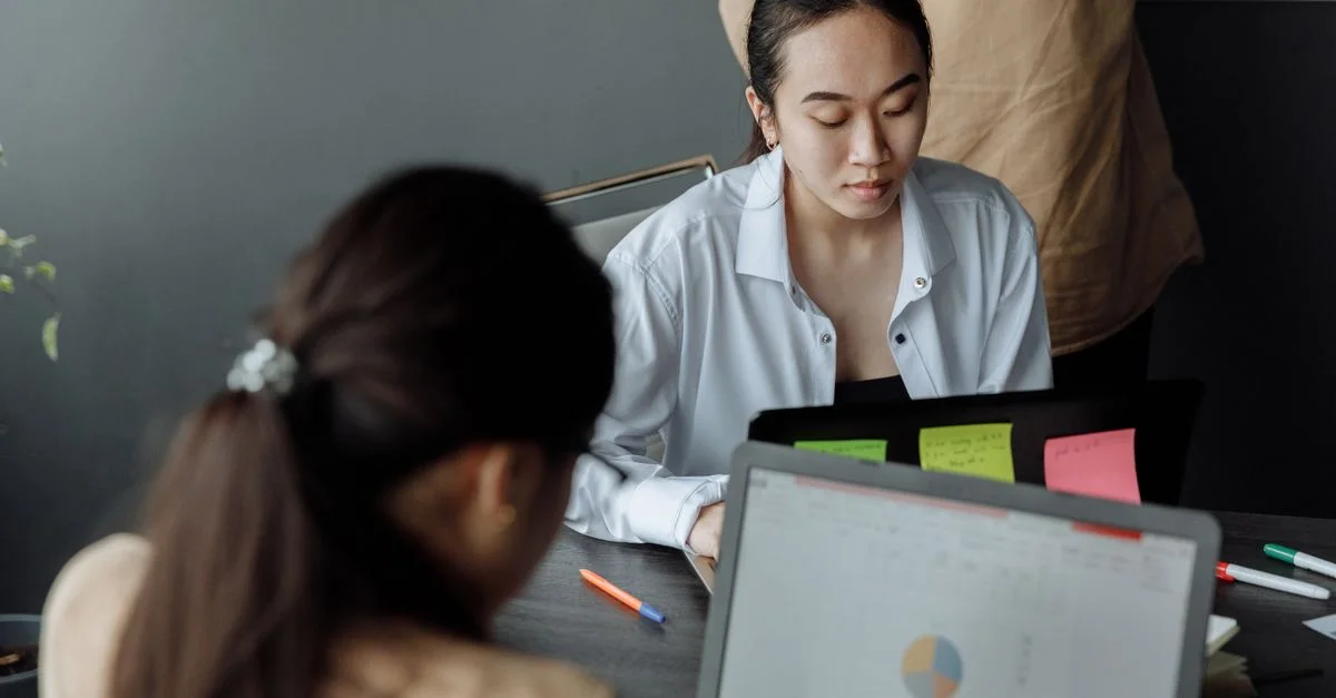Jeunes professionnels collaborant dans un bureau moderne avec des ordinateurs portables et des documents.