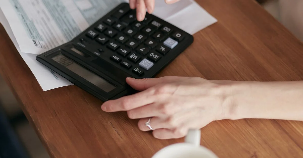 Une femme utilise une calculatrice pour gérer ses finances à la maison, concentrée sur la planification budgétaire.